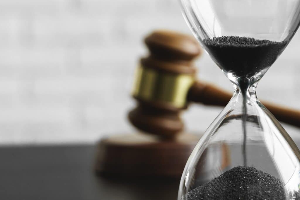 Court concept Hourglass and judge gavel on table